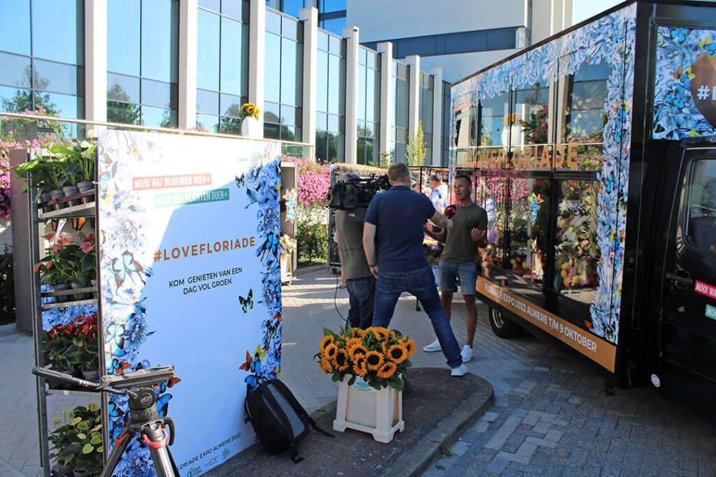 TV Flevoland interviews TV gardener Ivo Puman in front of the mobile greenhouse.  - Photo: Ton van der Scheer