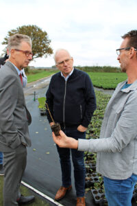 Peter van der Avoird (rechts) laat een zaailing van de kiri-boom zien aan minister Adema (midden) en Michiel van Ginkel (links) van de Tuinbouwondernemersprijs.